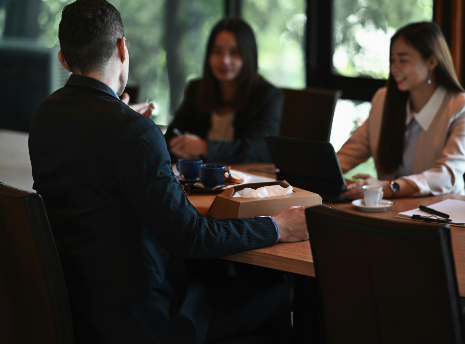 Three employees sat around a board table having a sensitive discussion