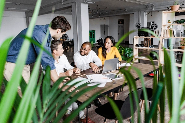 A group of colleagues discusses work in a modern office setting.