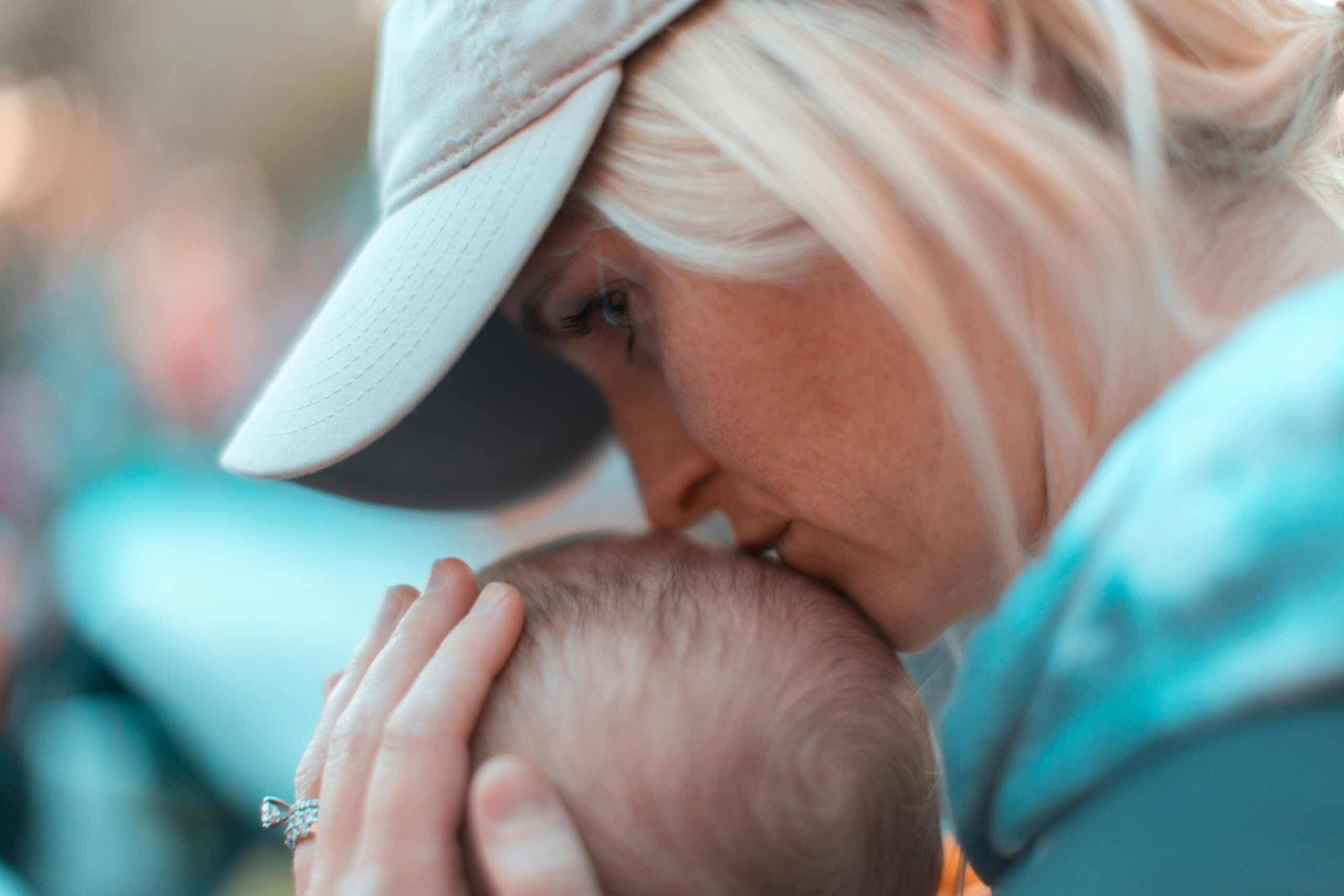 A woman kisses a small baby's head.