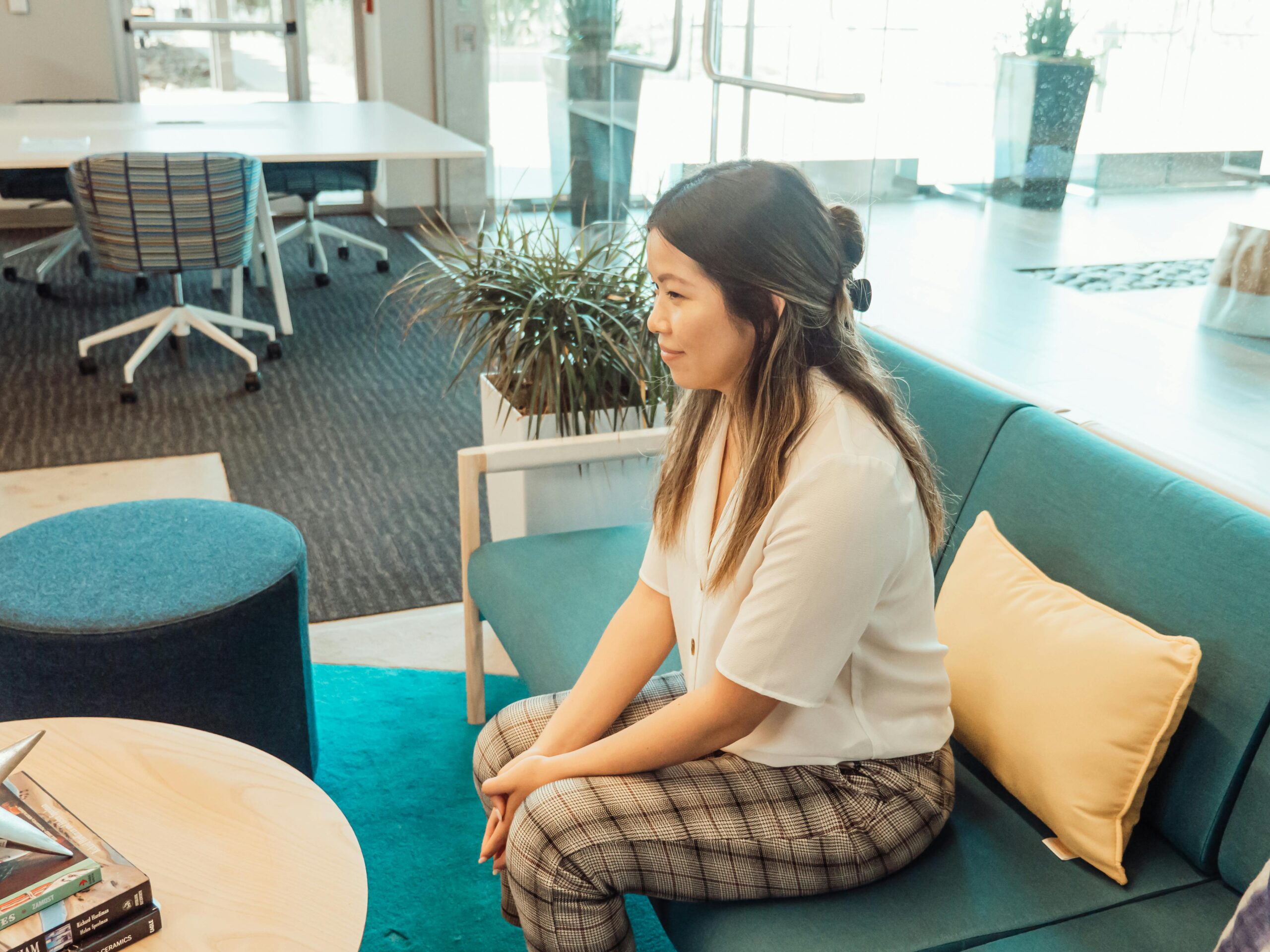 Woman sits on a green counselling couch along. She is lent forward as if in deep concentration with someone opposite.